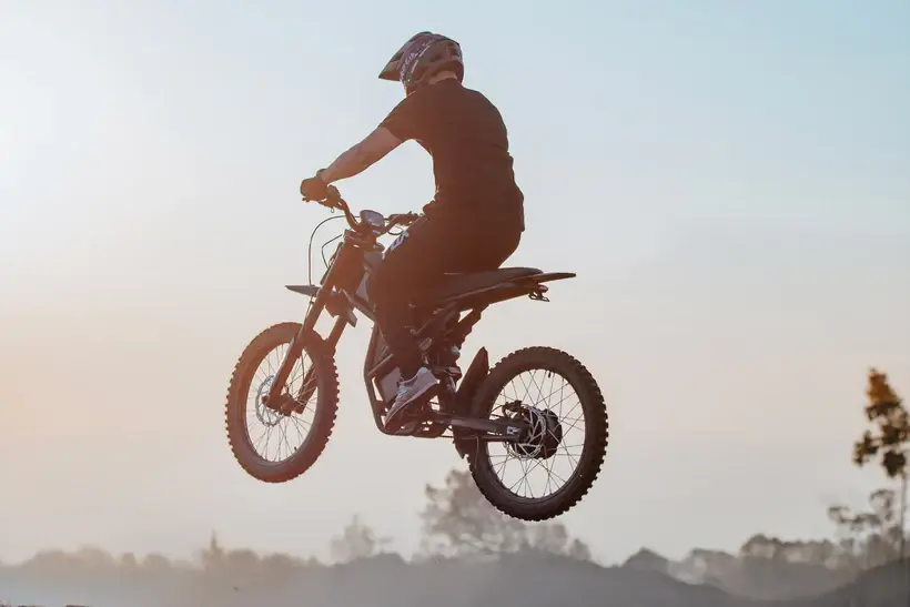 GT73 elektrinis dviratis 1000W ore atliekant šuolį, galingas off-road elektrinis dviratis su motocross dizainu saulėlydžio fone