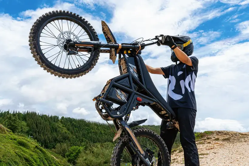 GT73 PRO elektrinis dviratis 1500W atliekantis wheelie bekelėje su motociklininku kalnuotoje vietovėje